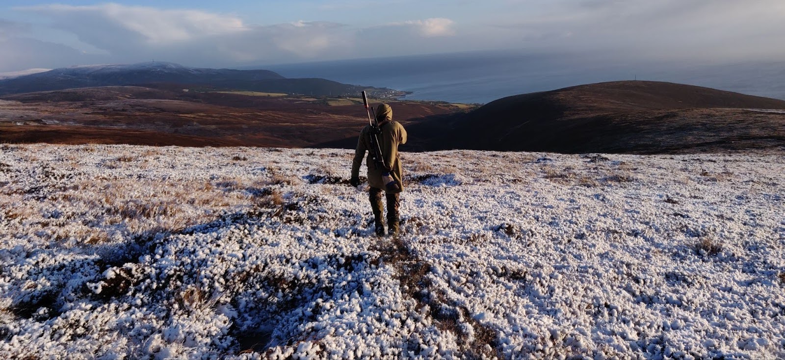 A person standing on a snowy hill, enjoying the winter landscape from the highest point.