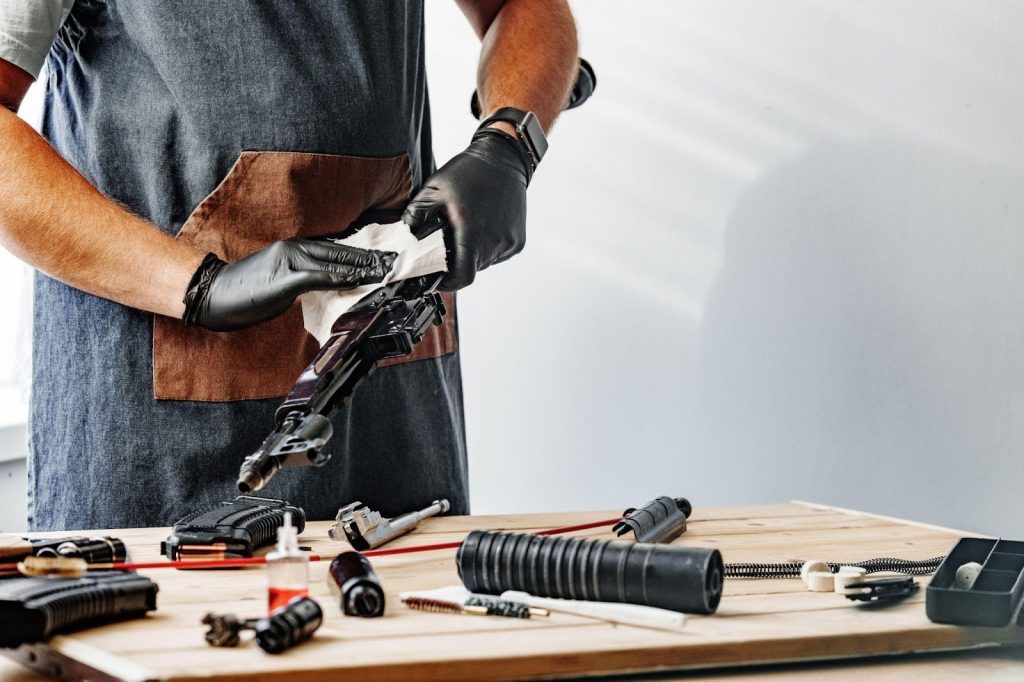 A man in an apron and gloves diligently works at a table, surrounded by an array of tools